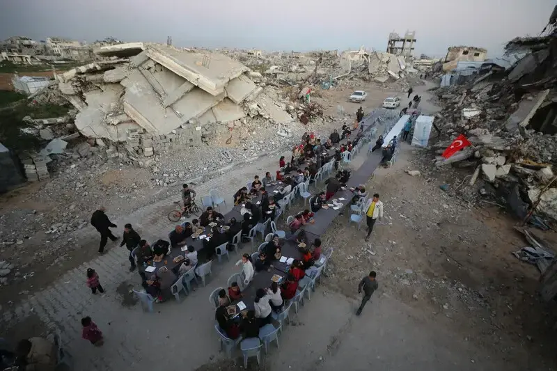 Palestinos desplazados se re&uacute;nen para su comida iftar de ruptura del ayuno entre los escombros de edificios destruidos en la ciudad de Gaza, 25 de febrero de 2026 - Omar Ashtawy / APA Images.